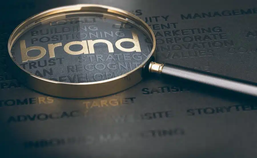 Brand marketing and management, branding or rebranding concept. 3d illustration of a magnifying glass over golden and black words.