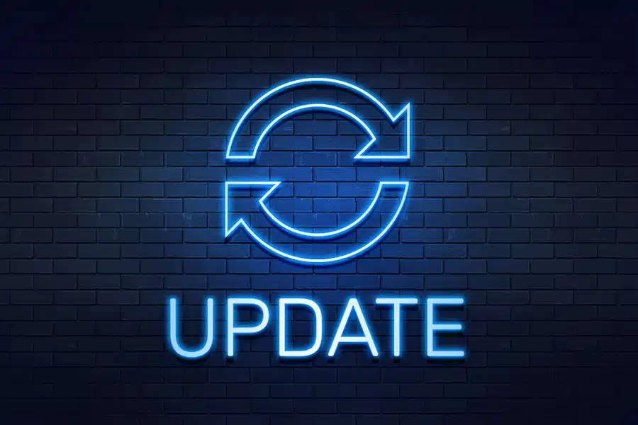 Neon "update" sign with accompanying graphic against a dimly lit brick wall