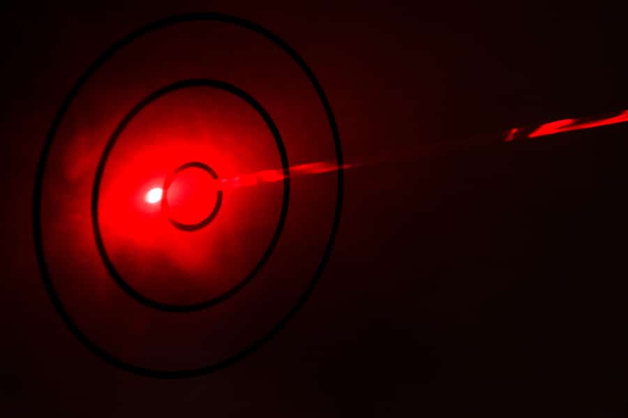 A red laser beam visualised through smoke hitting a simple target