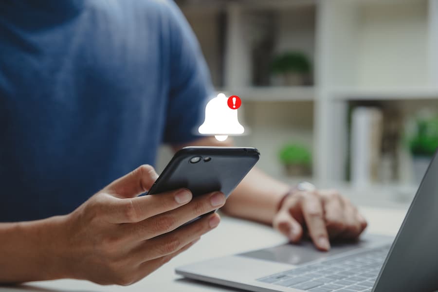 Notification concept, Young man using phone with notification bell alert.