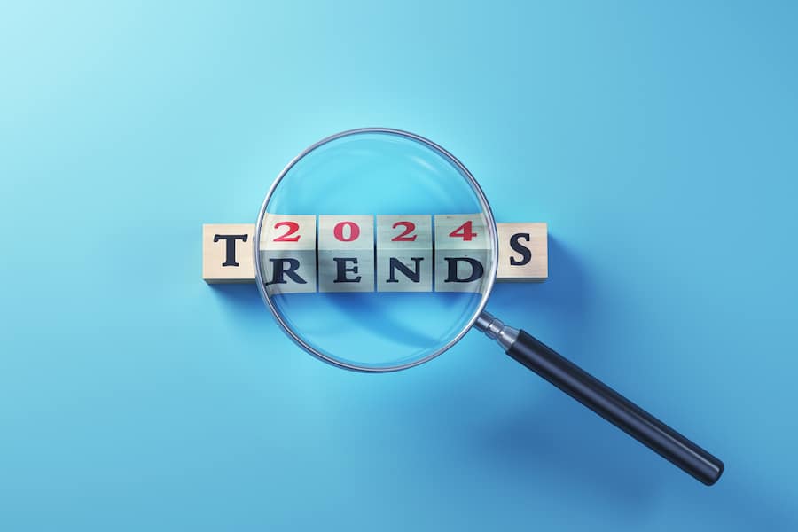 3d Render, 2024 Trends Written on Wooden Blocks Standing Selected with Magnifying Glass on Blue Background (close-up)