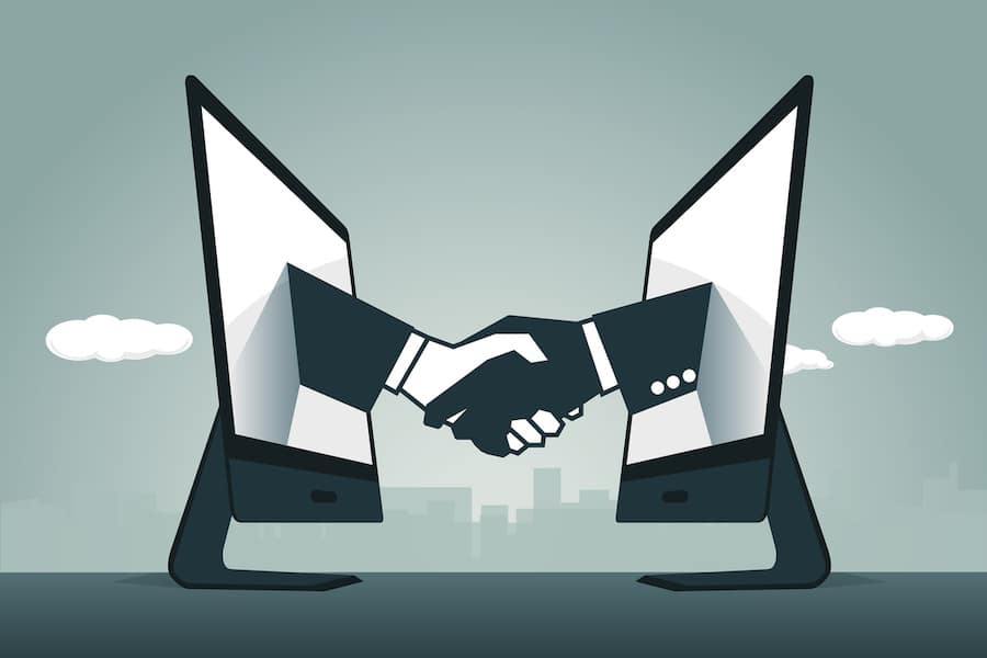 Virtual handshake concept. Two computers facing each other with and handshake happening in the middle. Reaching through the screen and giving a handshake