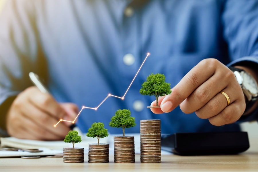 Saving money and investment concept. Businessmen put a coin with a tree that grows and a tree that grows on a pile of money. The idea of maximizing the profit from the business investment.