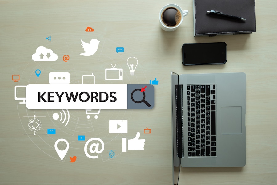 "Keywords" with graphics around the word next to a laptop, phone, notepad, and cup of coffee