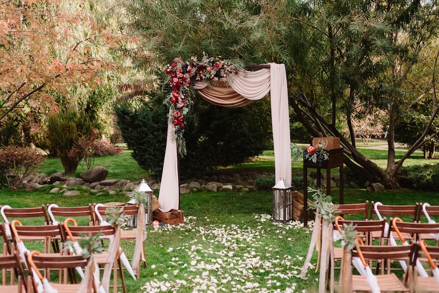 Autumnal wedding archway decoration of roses, apples, grape and pomergranate, in red colour, closeup