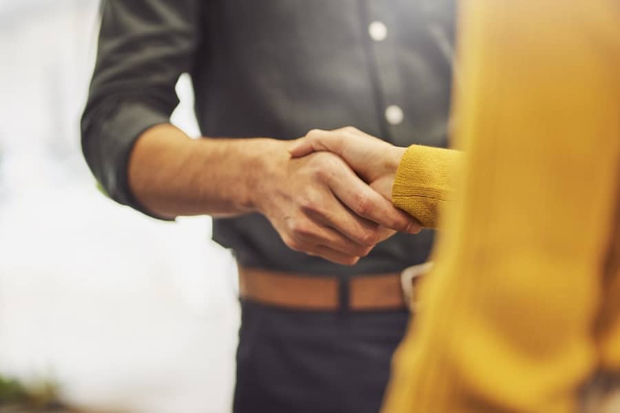 Businessman greeting businesswoman with handshake