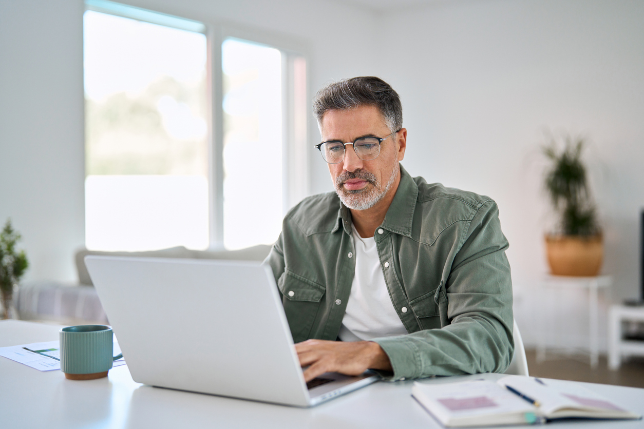 Older mature man wearing glasses using laptop computer to make a reservation for travel